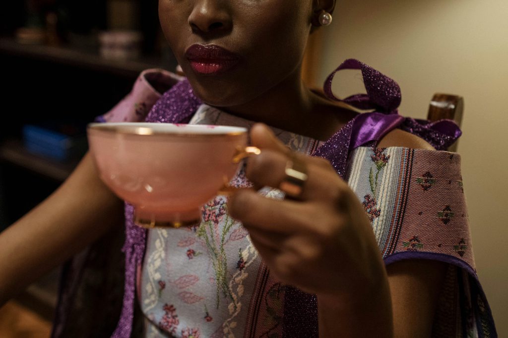 pexels photo 6869640 6869640 Stylish woman in vibrant dress sipping tea from a porcelain cup in a cozy indoor setting.